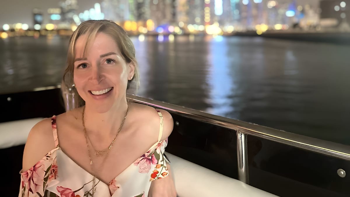 Christine McDannell on a boat at night with the Dubai Marina skyline behind her